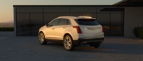 White Cadillac parked in driveway facing a house.