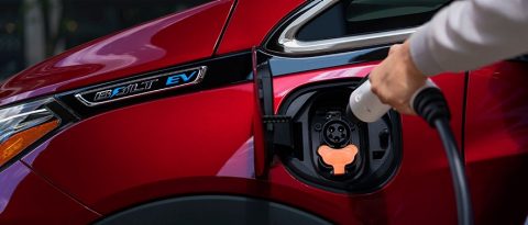 someone unplugging a red Chevy Bolt