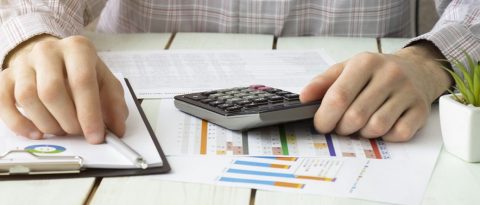 Man with calculator and budgeting sheets at a table
