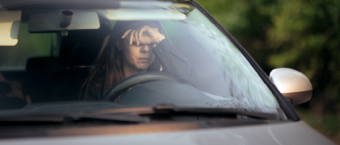 A woman behind the wheel of a car holds her head in frustration following a fender bender.