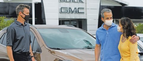 Customers in masks inspecting their new lease vehicle