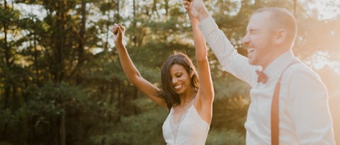 Newlyweds celebrating getting married by holding hands in the air