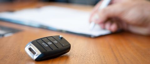 Key fob next to person signing a contract for a new GM vehicle